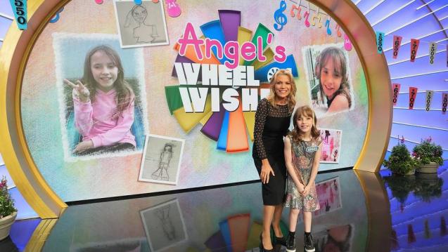 Wisk kid Angel standing on the Wheel of Fortune stage with Vanna White celebrating her wish coming true.
